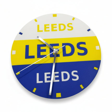 A circular vintage-style Leeds gas station wall clock with a white, yellow, and blue color scheme and silver hands, photographed on a neutral light gray background.